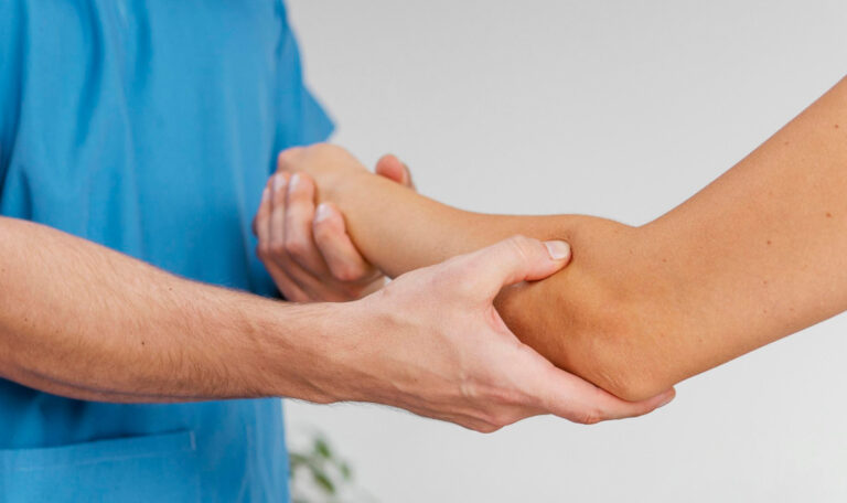 Physical therapists massages elbow area of a patients arm during Orthopedic Physical Therapy rehabilitation treatment