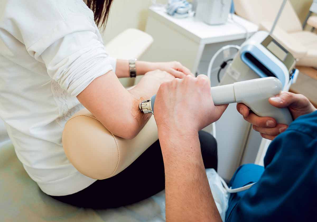 Female patient receives ultrasound physical therapy treatment for elbow pain