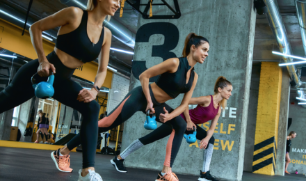 Woman doing kettle-bell weight strengthen exercises during a gym class