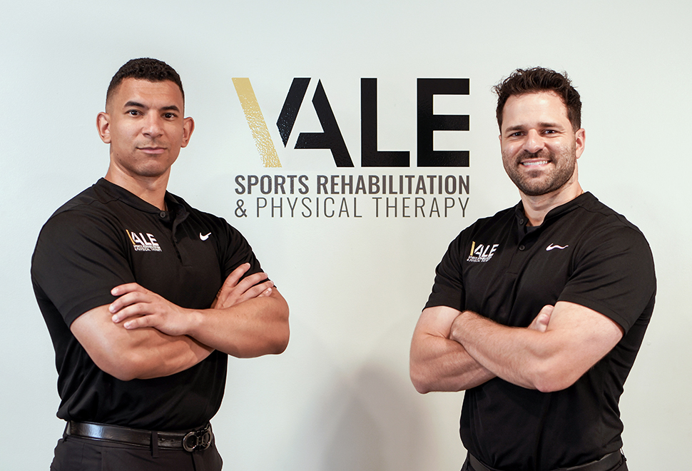 Physical therapy doctor's Frankie Goris and Adrian Lorenzo standing in front of Vale logo